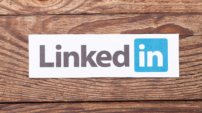 The LinkedIn logo, cut out and pasted onto a wooden background