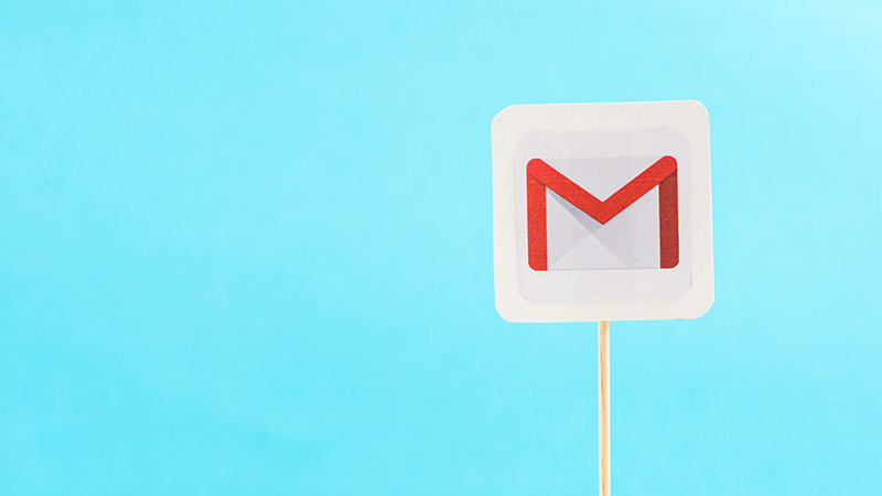 The Gmail app icon, cut out and posted on a popsicle stick